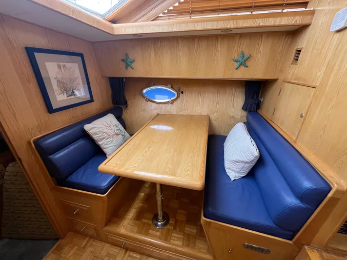 Journey Yacht Photos Pics Cozy dining nook in 1999 Ocean Alexander Sundeck 460 with blue seating and wooden table.