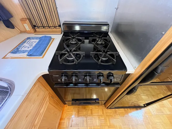 Journey Yacht Photos Pics 1999 Ocean Alexander Sundeck 460 kitchen with black stove and wooden cabinetry.