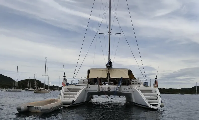  Yacht Photos Pics 2004 Lagoon 570 catamaran anchored in a serene bay with surrounding sailboats.