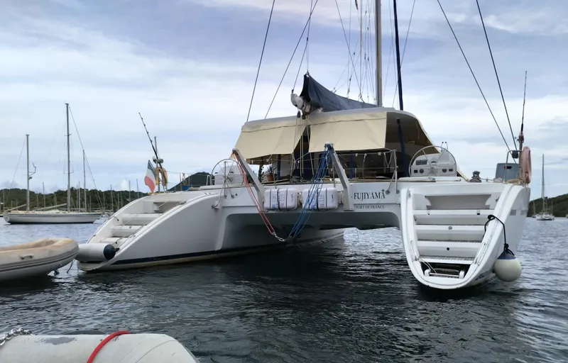  Yacht Photos Pics 2004 Lagoon 570 catamaran anchored in calm waters with a small dinghy attached.