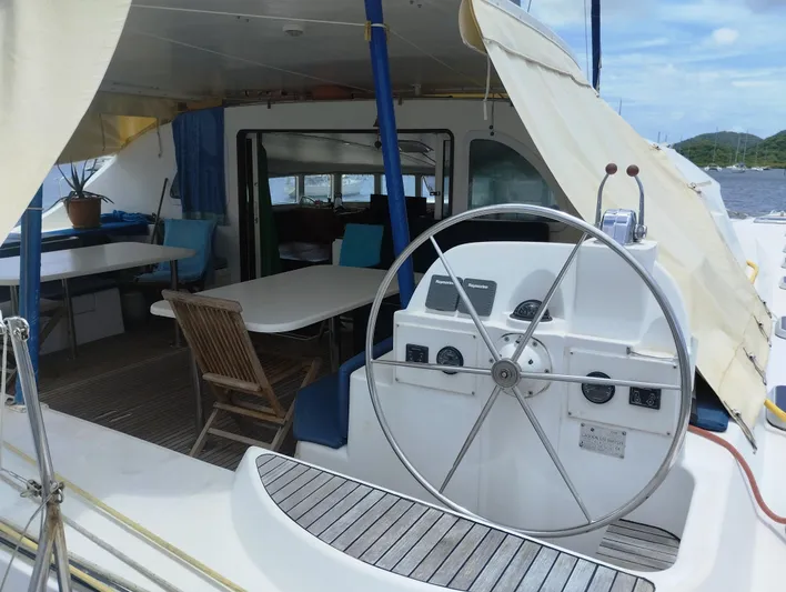  Yacht Photos Pics 2004 Lagoon 570 yacht cockpit with steering wheel, seating, and table under canopy.
