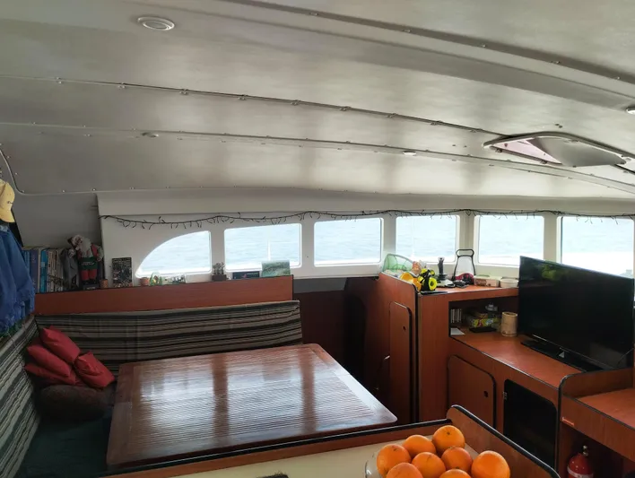  Yacht Photos Pics Interior of 2004 Lagoon 570 yacht with dining area, TV, and fruit bowl.