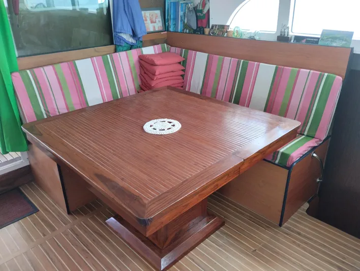  Yacht Photos Pics Cozy dining area on 2004 Lagoon 570 yacht with striped cushions and wooden table.