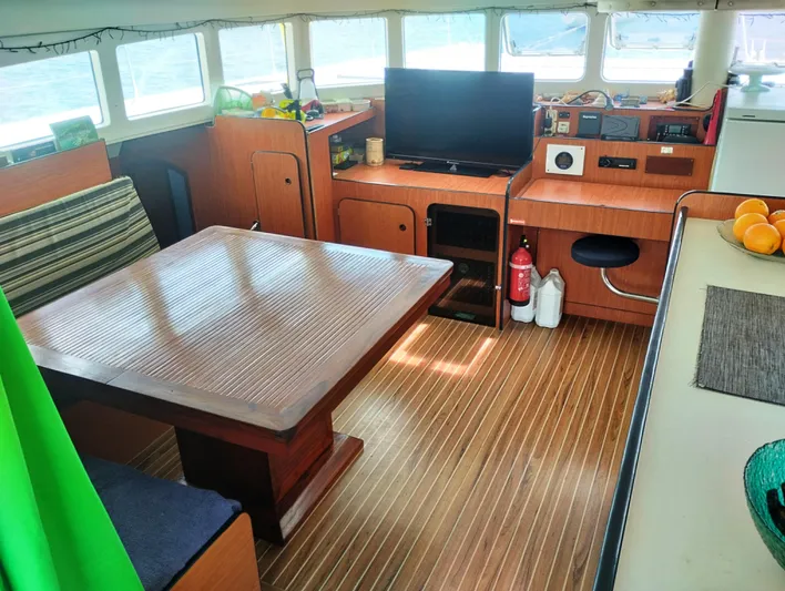  Yacht Photos Pics Interior of a 2004 Lagoon 570 yacht with wooden flooring, dining area, and entertainment setup.