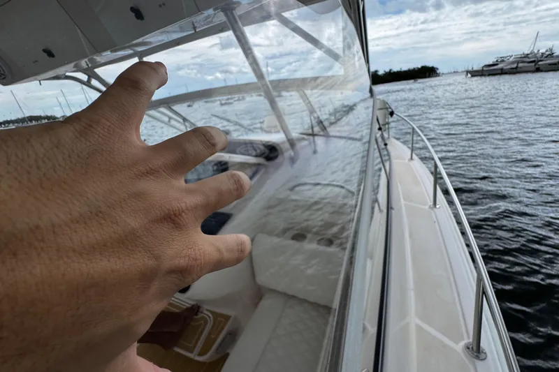  Yacht Photos Pics Hand reaching towards the helm of a 2001 Grady-White Express 330 boat on the water.