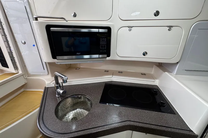  Yacht Photos Pics Compact kitchen area in a 2001 Grady-White Express 330 boat with sink, stove, and microwave.