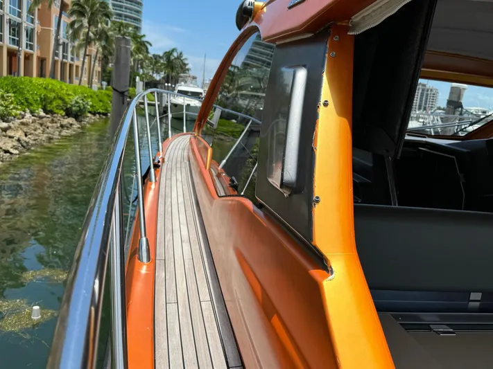 Onkor II Yacht Photos Pics 2015 Azimut Atlantis 43 yacht with orange detailing, docked near lush greenery.