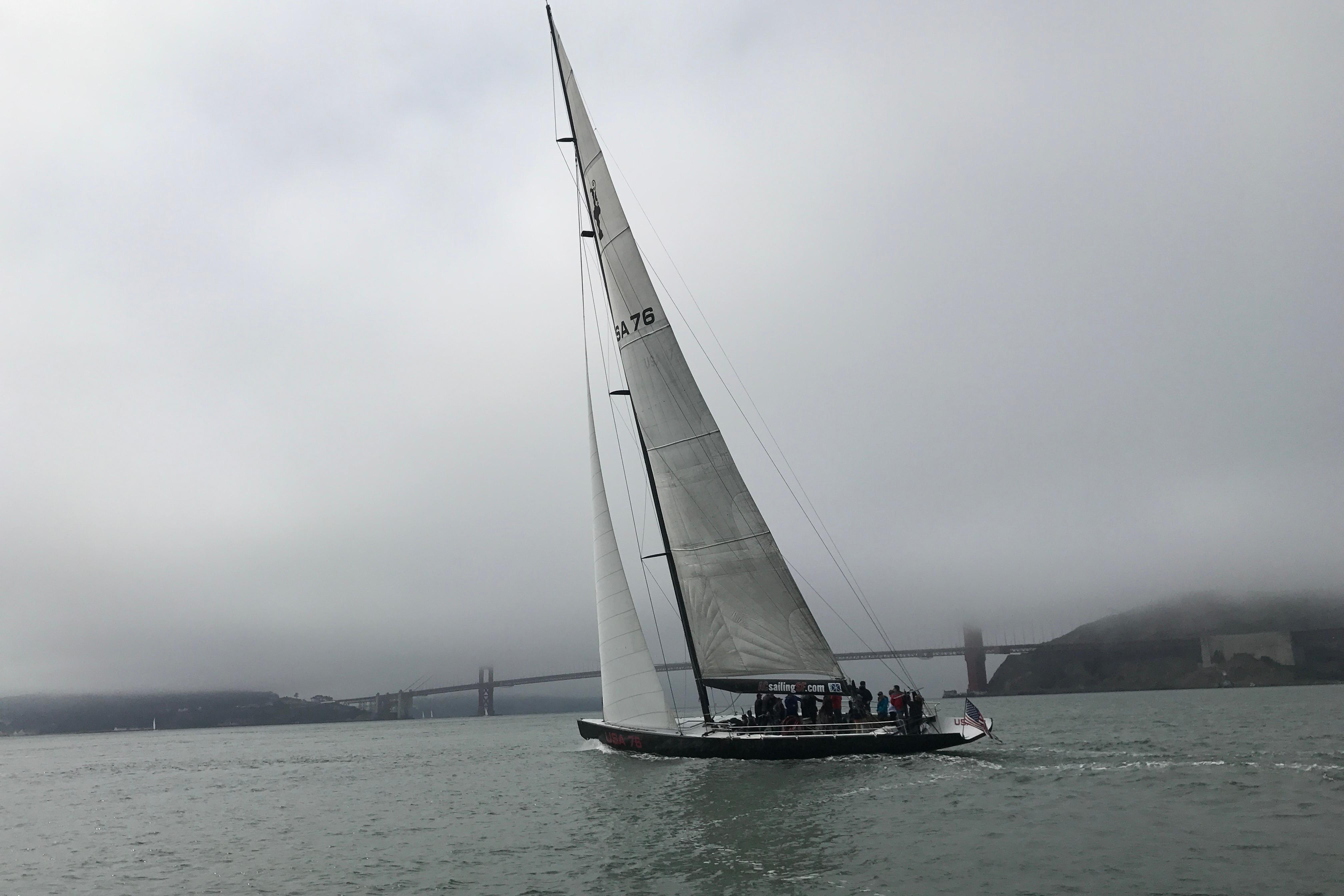 Sailing yacht on foggy waters near a bridge, 2002 International Americas Cup Class.