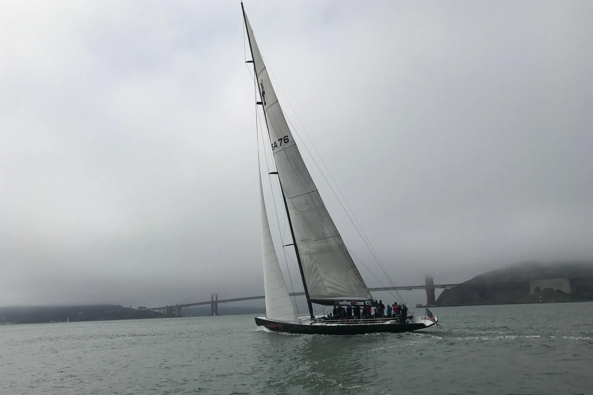 Sailing yacht on foggy waters near a bridge, 2002 International Americas Cup Class.