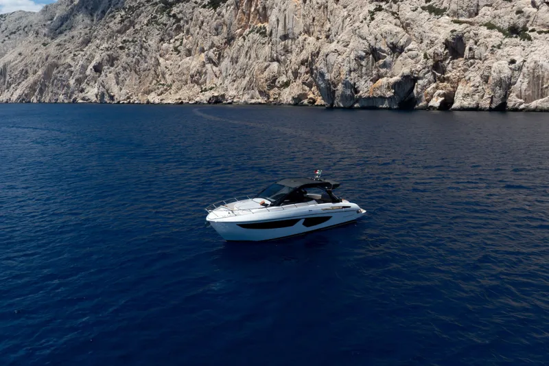  Yacht Photos Pics 2026 FIM 440 Regina yacht cruising near rocky coastline in deep blue sea.