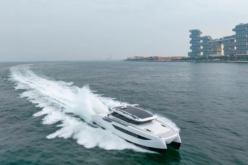  Yacht Photos Pics 2026 Sunreef Ultima 55 yacht cruising near modern waterfront architecture.