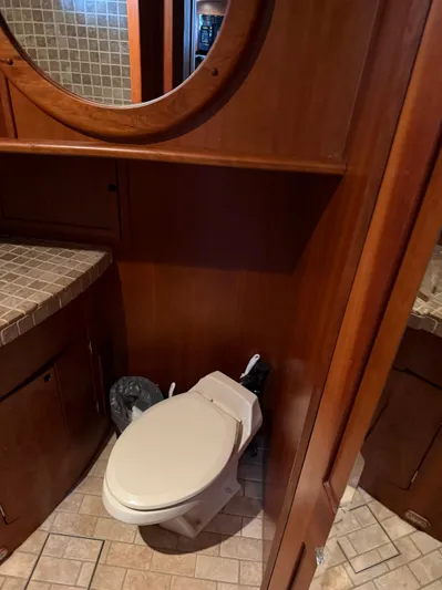 Passage Yacht Photos Pics Compact bathroom on a 2009 Custom Dutch Canal Barge with wooden cabinetry and tiled surfaces.