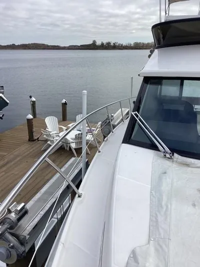  Yacht Photos Pics 2018 Regal 42 Fly yacht docked by a serene lake with Adirondack chairs.