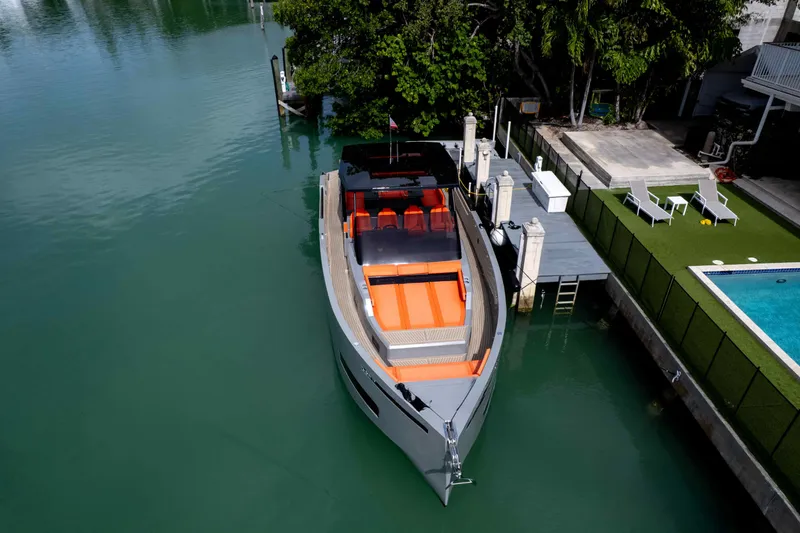  Yacht Photos Pics 2023 De Antonio Yachts D50 docked near a pool, showcasing sleek design and vibrant seating.