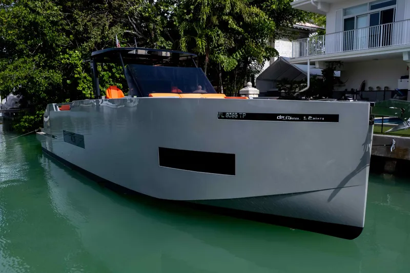  Yacht Photos Pics 2023 De Antonio Yachts D50 docked near a modern waterfront home.