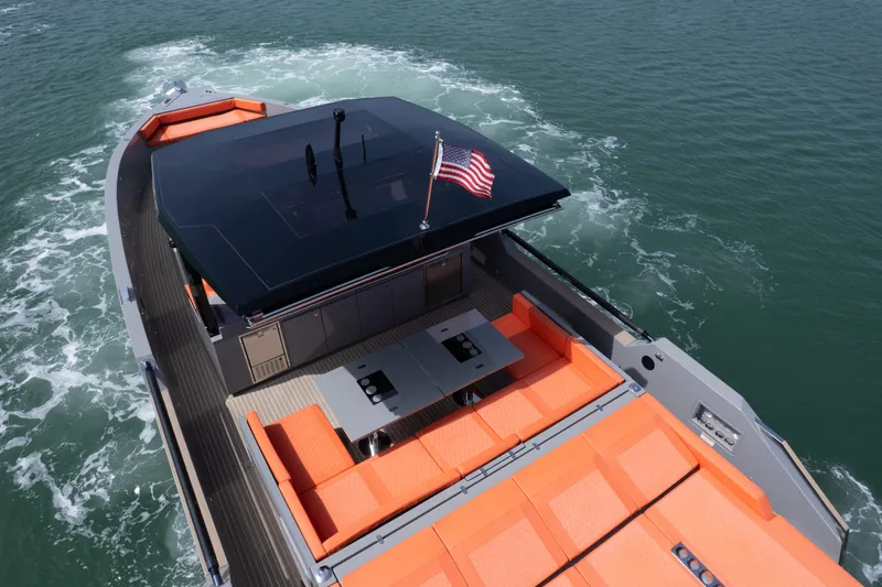  Yacht Photos Pics 2023 De Antonio Yachts D50 with orange seating, American flag, cruising on water.