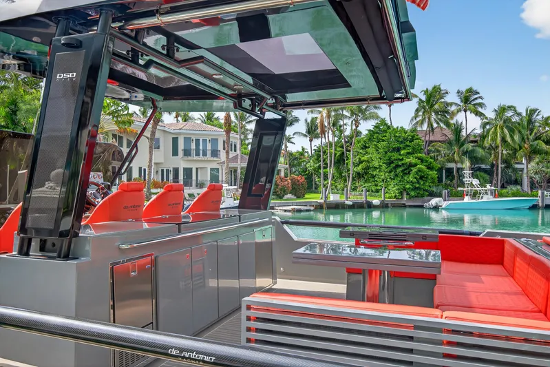  Yacht Photos Pics Luxurious 2023 De Antonio Yachts D50 with sleek design and vibrant red seating, docked by waterfront homes.