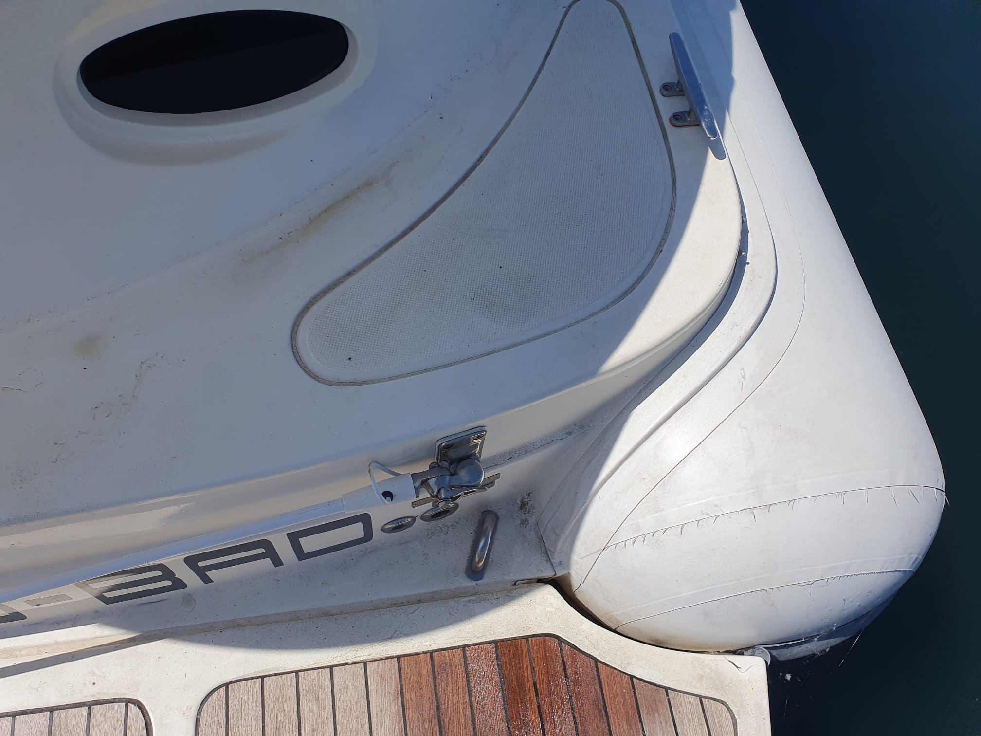 Close-up of a boat's inflatable section and deck, featuring a latch and wooden flooring.