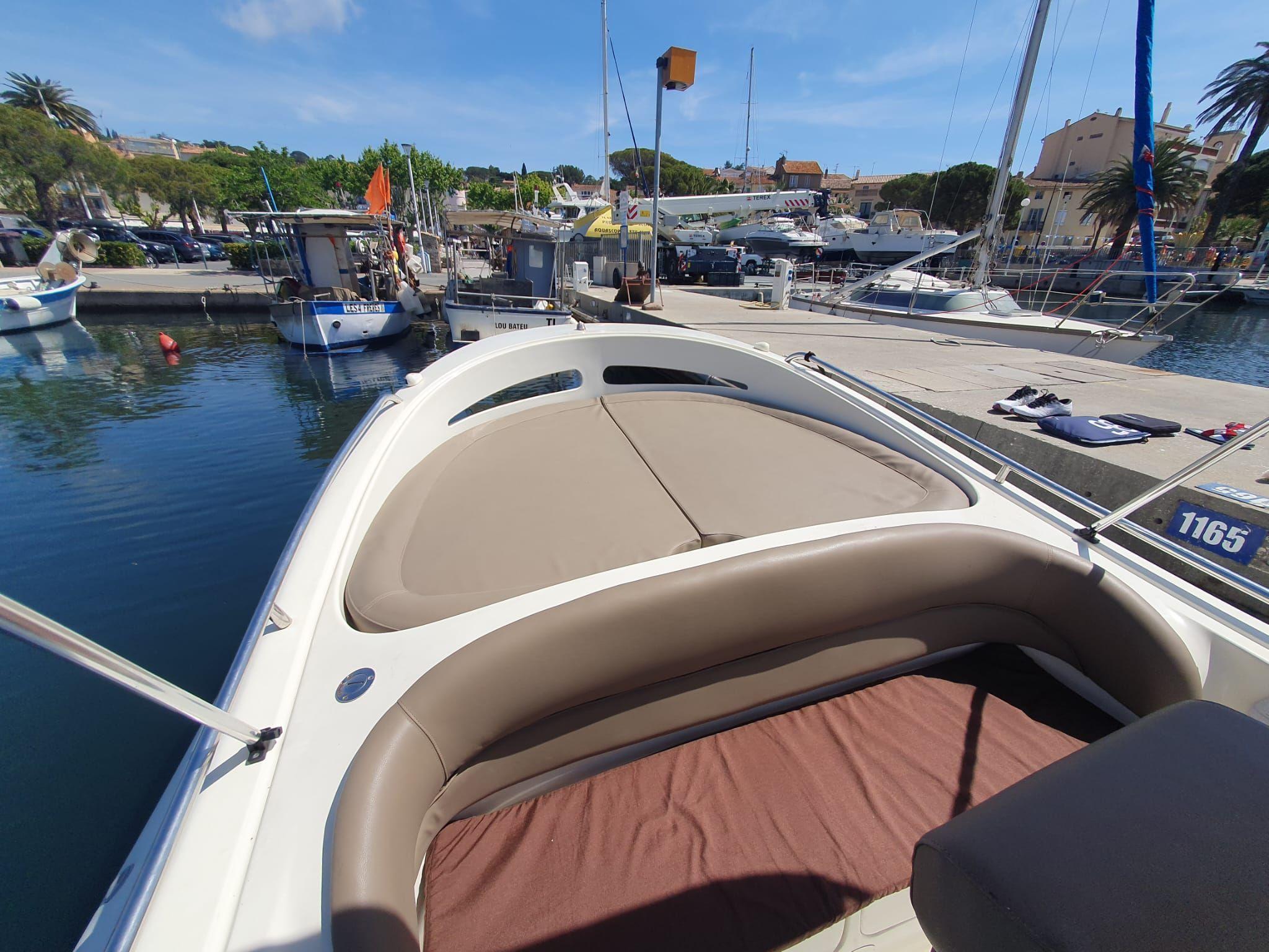Bow of a boat docked at a marina, featuring cushioned seating and clear blue skies.