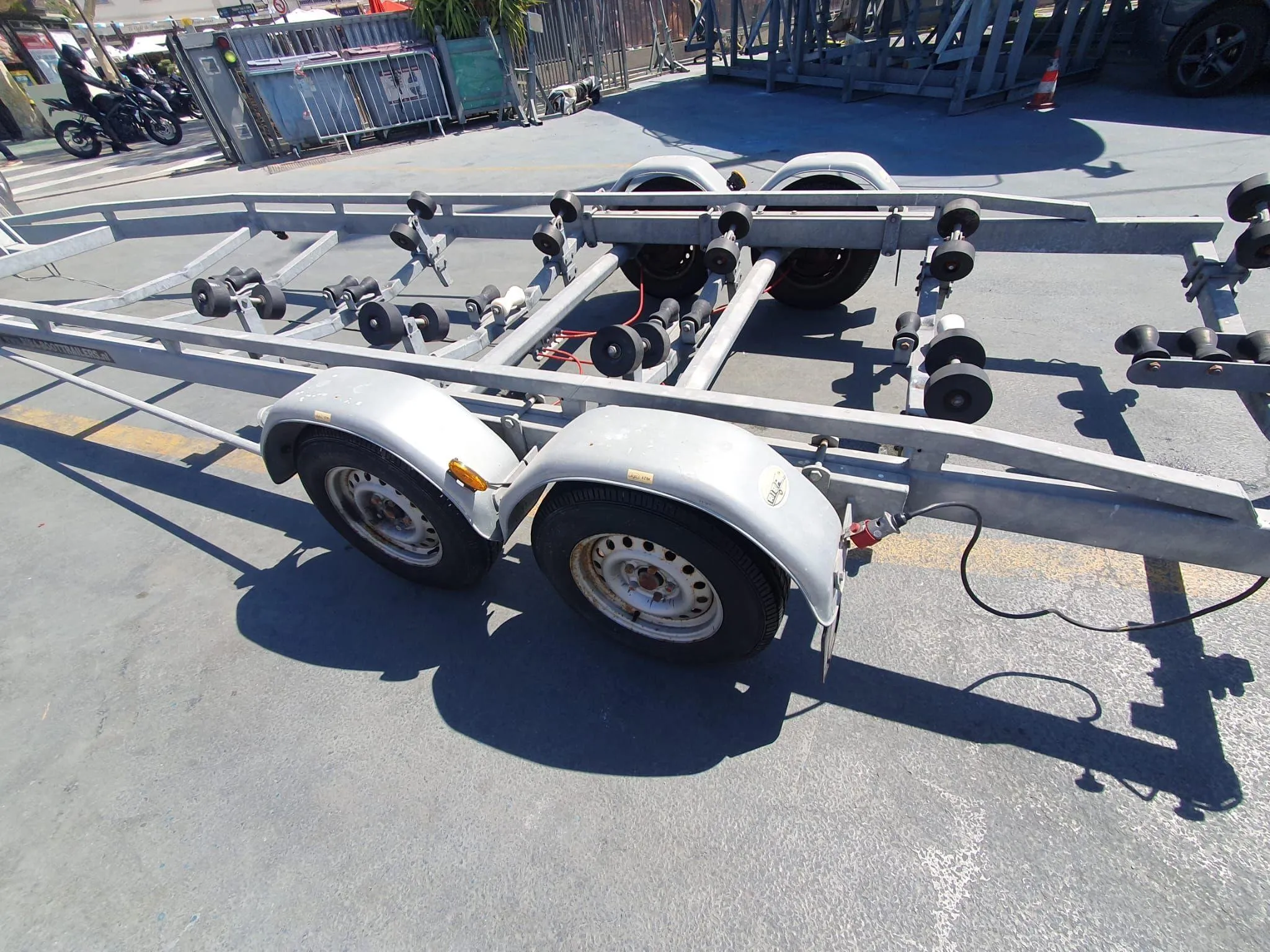 Boat trailer with dual axles and rollers on a sunny day.