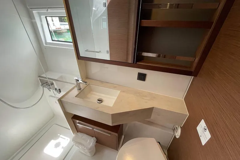 Sand Dollar Yacht Photos Pics Modern bathroom in 2023 Lagoon 46 yacht, featuring sleek sink and wooden cabinetry.