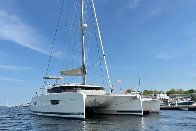 White Cap IV Yacht Photos Pics 2024 Fountaine Pajot Astrea 42 catamaran docked on calm water under clear blue sky.