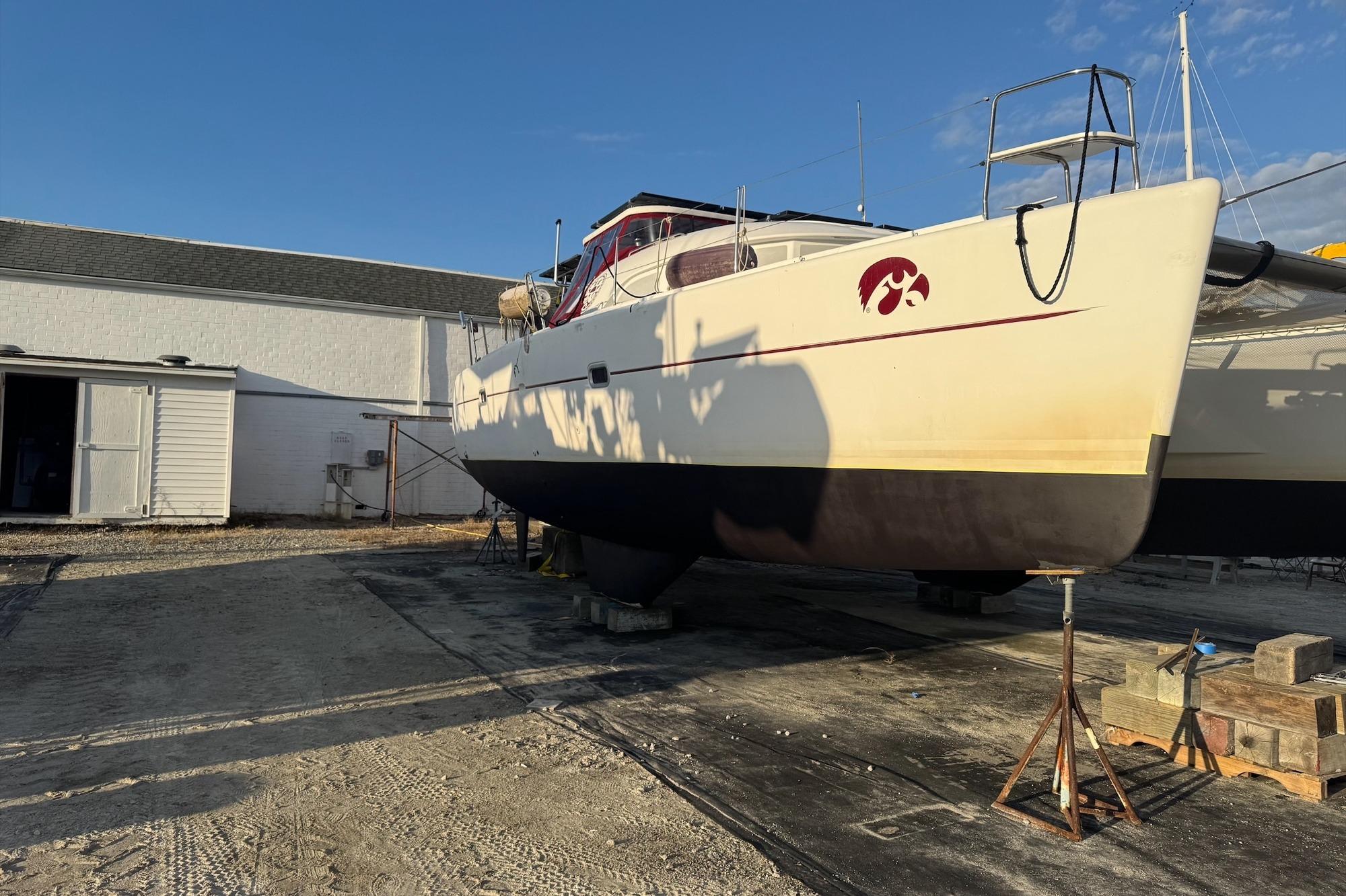 2004 Lagoon 380 catamaran on dry dock, with clear blue sky background.