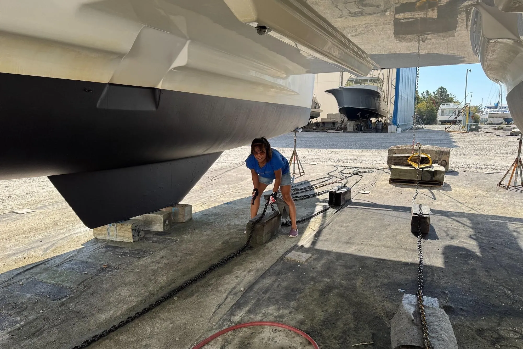 Person working on a 2004 Lagoon 380 catamaran in a boatyard.