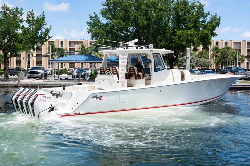  Yacht Photos Pics 2022 SeaVee 450z boat with quad engines, docked near a marina, surrounded by trees and buildings.