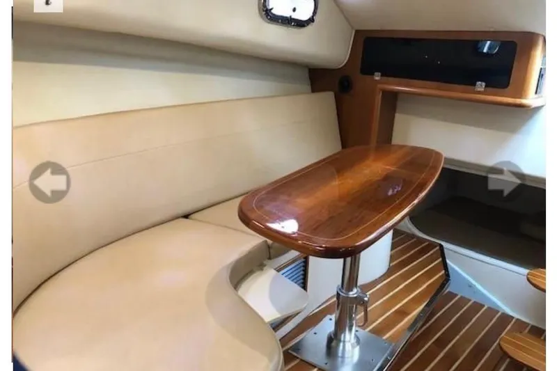 Good Fun Yacht Photos Pics 2006 Pursuit 3370 Offshore cabin interior with beige seating and wooden table.