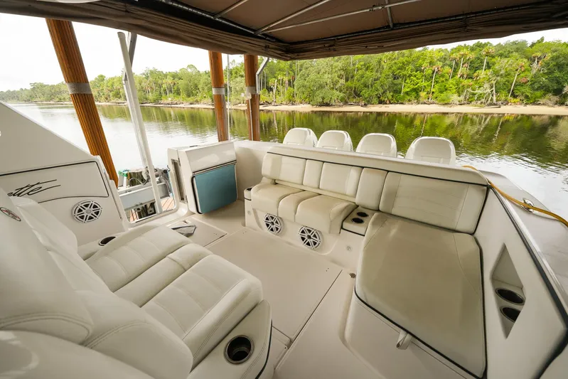  Yacht Photos Pics 2015 Cigarette 42 Huntress boat interior with white seating, docked by a scenic river.