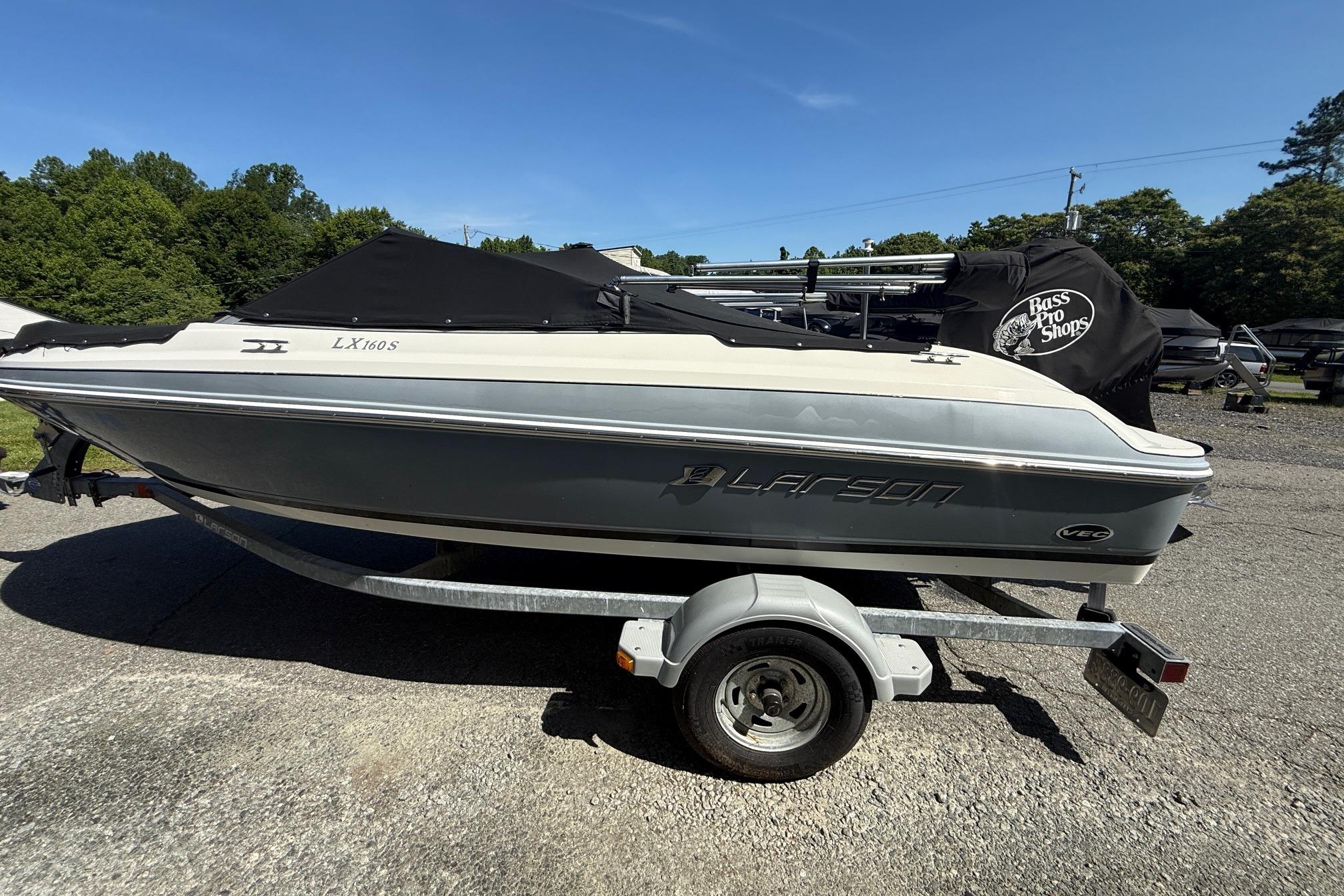 2014 Larson LX 160S OB boat on trailer, covered, outdoors, sunny day.
