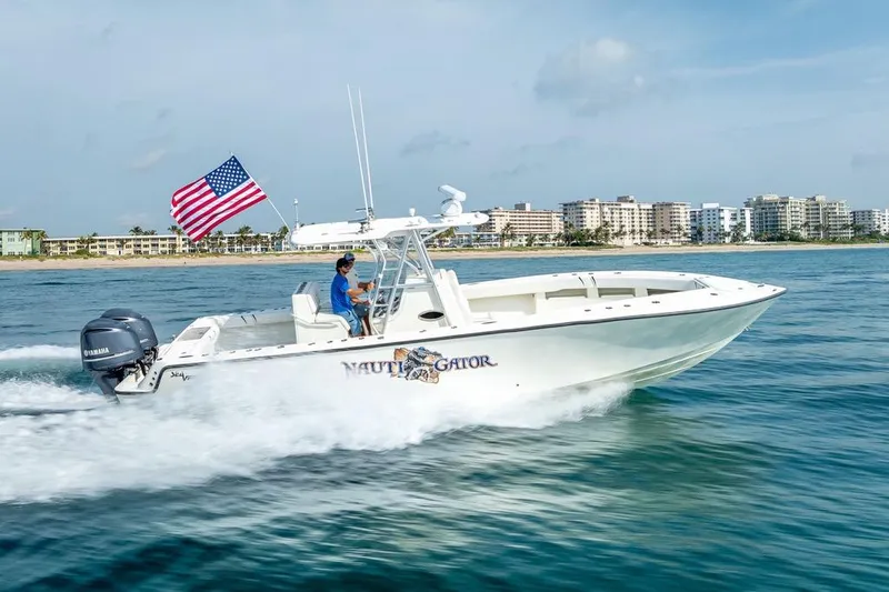 Nauti Gator Yacht Photos Pics 2014 SeaVee 34 boat cruising with American flag, coastal cityscape in background.