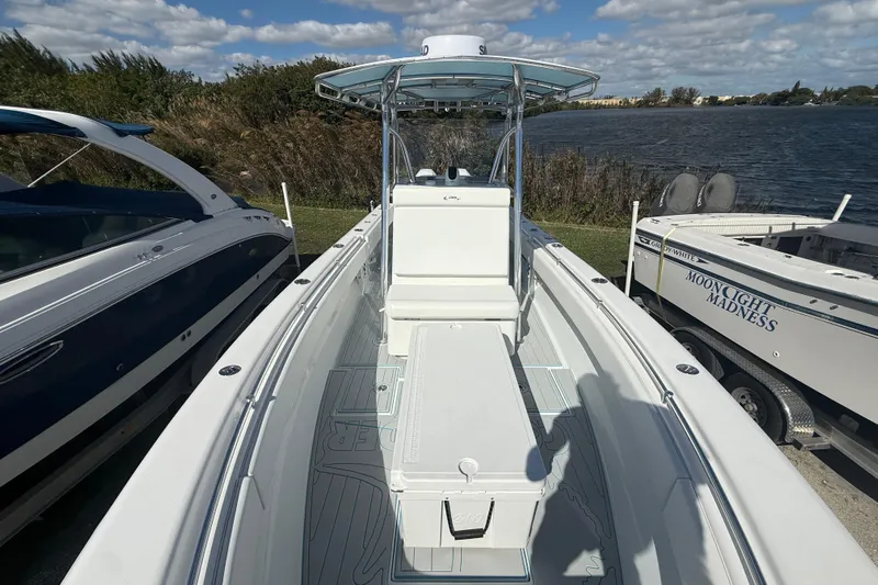  Yacht Photos Pics 2024 Contender 28 Tournament boat docked by a lake under a partly cloudy sky.