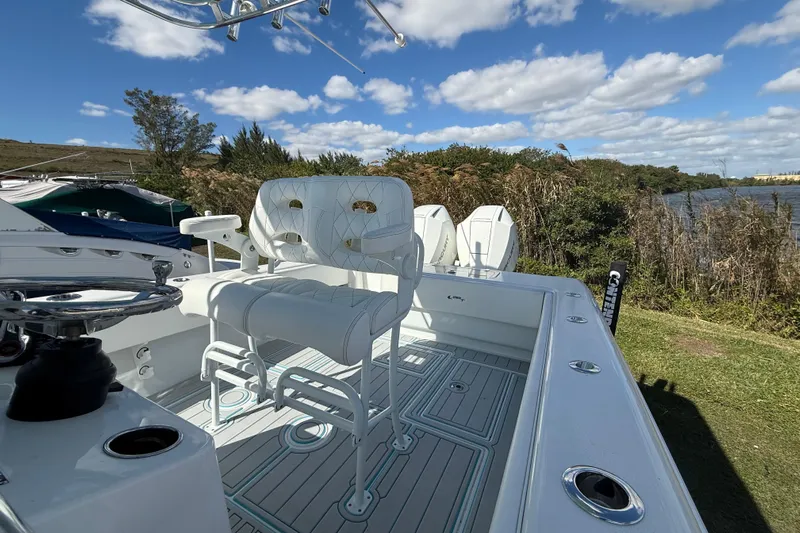  Yacht Photos Pics 2024 Contender 28 Tournament boat with white seating, docked near a scenic riverbank.