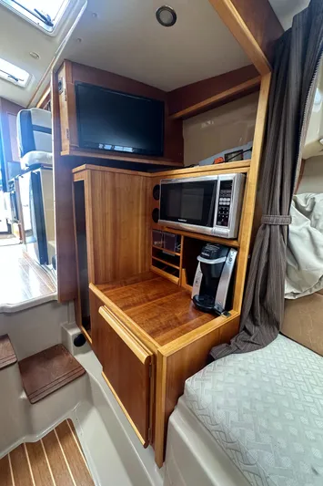 Cutwater 28 Yacht Photos Pics 2016 Cutwater 28 interior with TV, microwave, and coffee maker in wooden cabinetry.