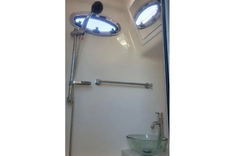  Yacht Photos Pics 2022 Regulator 41 boat bathroom with shower, glass sink, and porthole windows.