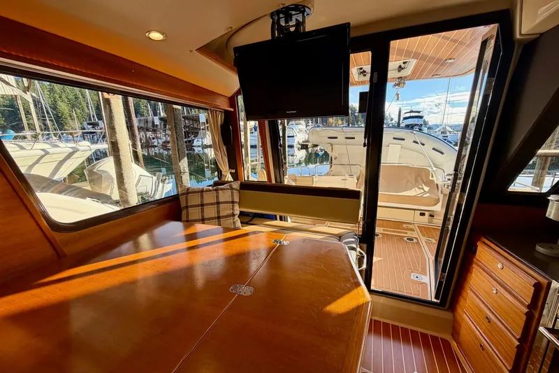 Bon Courage Yacht Photos Pics Interior of 2018 Ranger Tugs R-29 CB with wooden table, TV, and marina view.