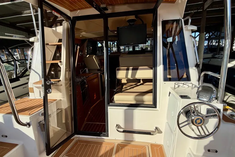 Bon Courage Yacht Photos Pics 2018 Ranger Tugs R-29 CB interior with helm, seating, and wooden flooring.