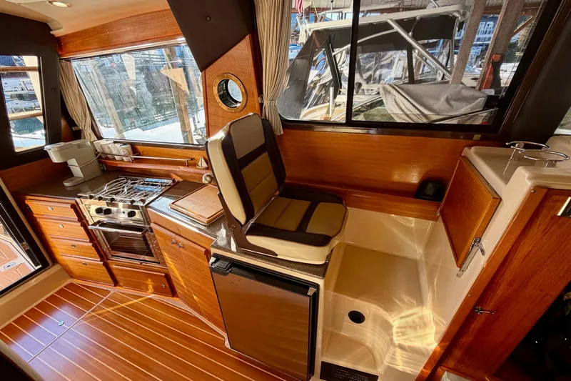 Bon Courage Yacht Photos Pics 2018 Ranger Tugs R-29 CB interior with wood finish, kitchen, and seating area.