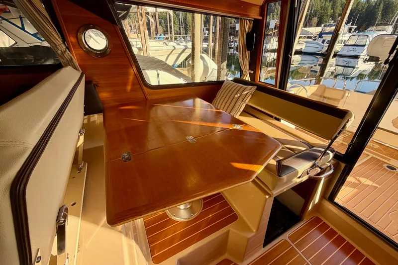 Bon Courage Yacht Photos Pics Interior of 2018 Ranger Tugs R-29 CB with wooden table and seating, docked at marina.