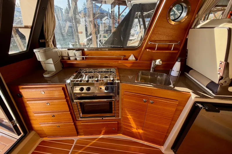 Bon Courage Yacht Photos Pics 2018 Ranger Tugs R-29 CB galley with stove, sink, and wooden cabinetry.