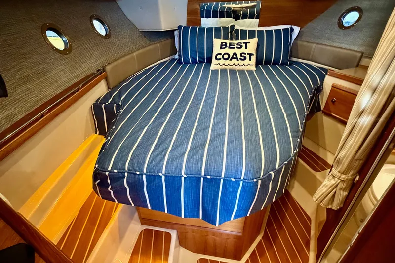 Bon Courage Yacht Photos Pics Cozy cabin interior of 2018 Ranger Tugs R-29 CB with striped bedding and "Best Coast" pillow.