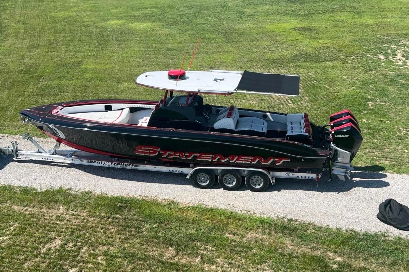 2018 Statement 380 Open boat on trailer, black and red design, parked on grass.