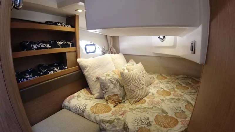  Yacht Photos Pics Cozy bedroom in a 2016 Beneteau GT35 yacht with patterned bedding and wooden shelves.