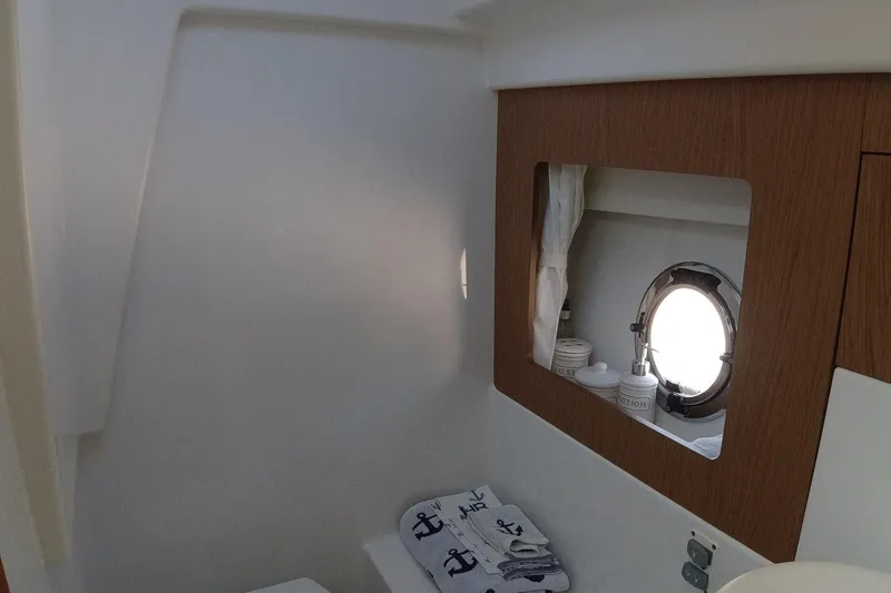  Yacht Photos Pics Beneteau GT35 2016 model bathroom with porthole, mirror, and nautical-themed towel.