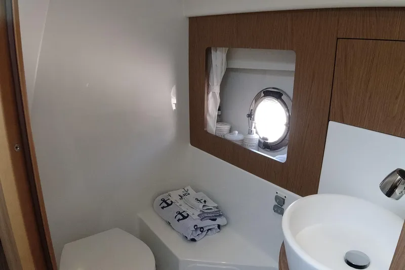  Yacht Photos Pics 2016 Beneteau GT35 bathroom with porthole, sink, and nautical-themed towels.