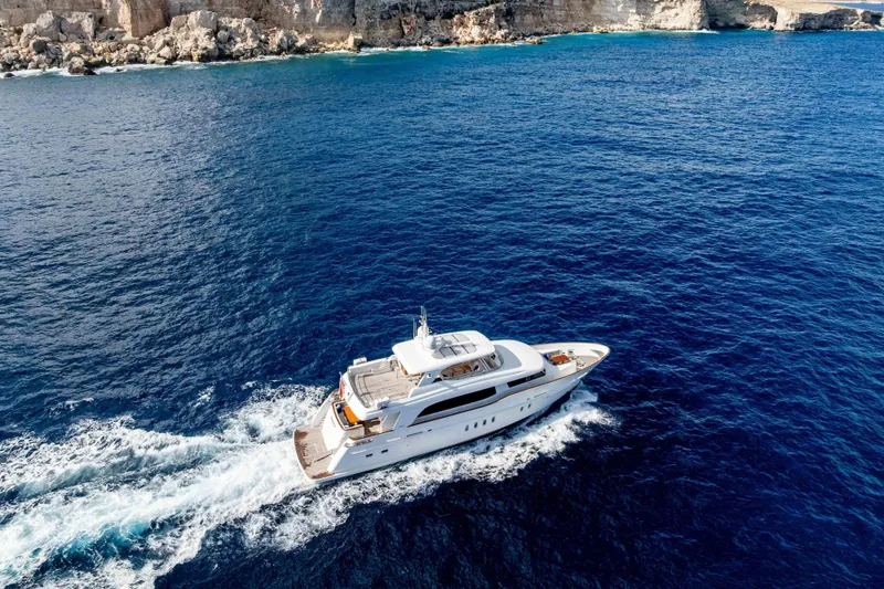 Firefly Yacht Photos Pics Luxurious 2015 Mulder 94 yacht cruising in clear blue ocean near rocky coastline.