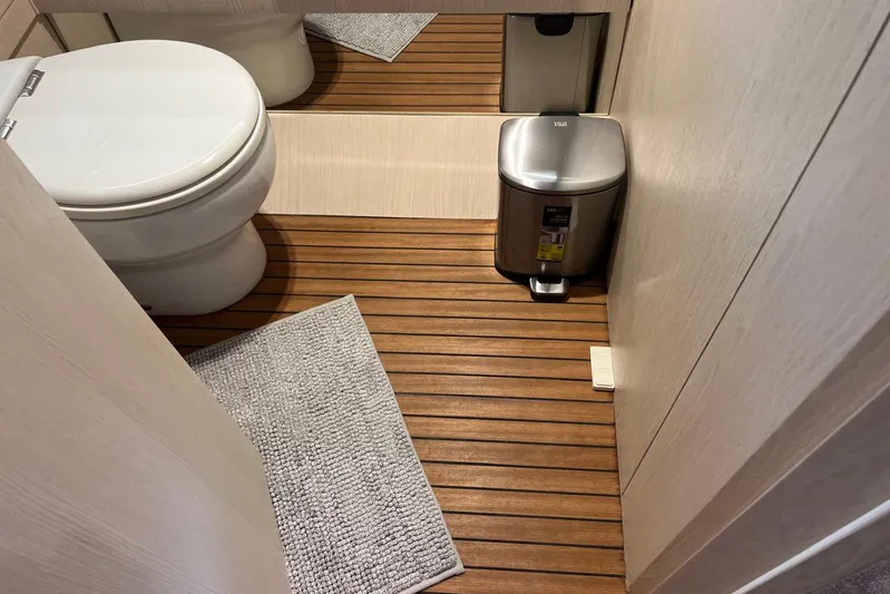  Yacht Photos Pics Luxury yacht bathroom with wooden flooring, modern toilet, and stainless steel trash bin. Azimut Grande 25M, 2020.