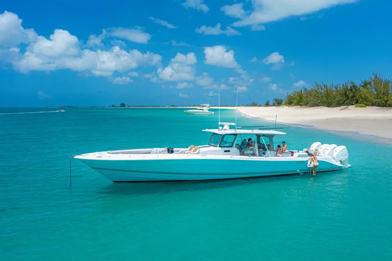 Relentless Yacht Photos Pics HCB 53 Sueños 2021 boat anchored near a tropical beach with clear blue water.